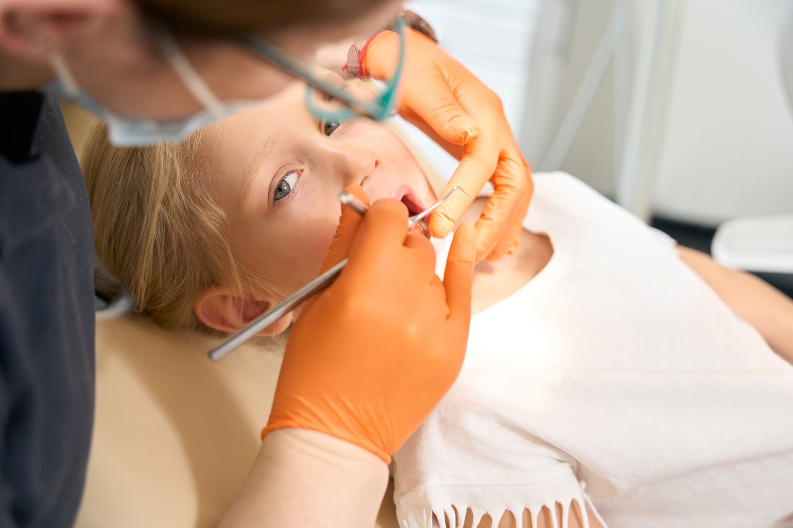 Children's dentist treats a girl's child's teeth